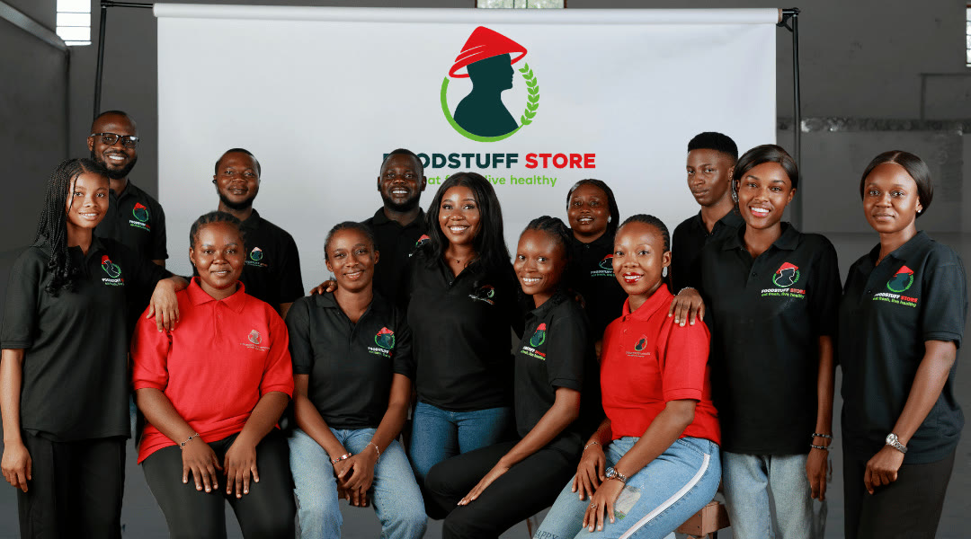The Foodstuff Store team in branded shirts in front of the company logo